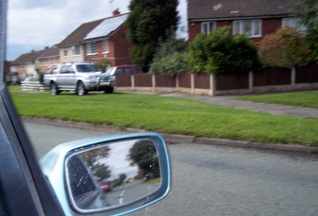 "In the rear view": Through my wing mirror I can see the erstwhile site of Red House Farm.  Those who farmed there are still commemorated, if you look for the evidence.