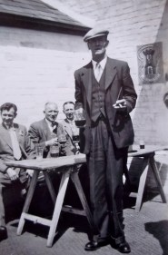 Dressed up to the nines on a club outing...How tall he is!  There's a swagger stick under his arm.  The young officers he encountered during the first war are duly ridiculed...to the entertainment of all. 